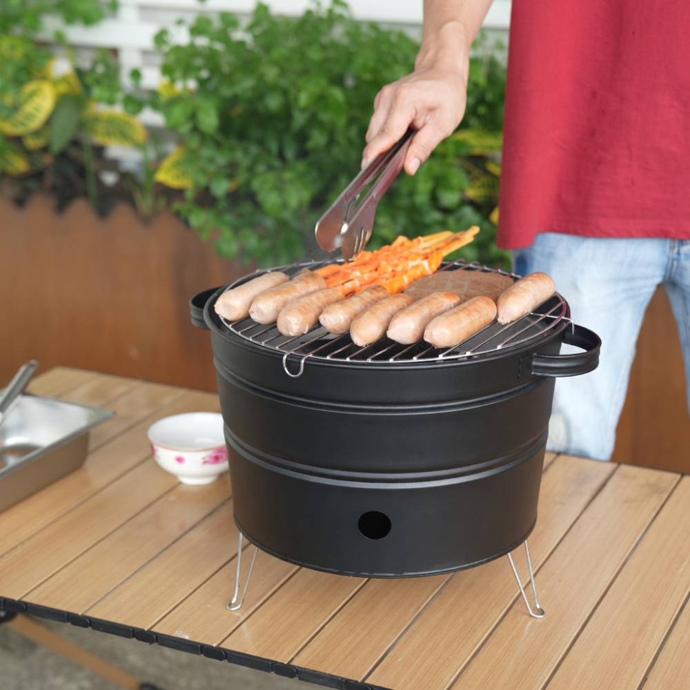 Mini barbecue à charbon portable noir, format compact avec poignées latérales et pieds stables, idéal pour pique‑niques, camping et petites terrasses.