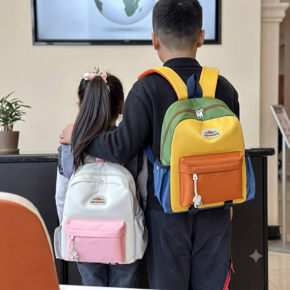 Sac à dos scolaire enfant multicolore, léger et résistant, avec compartiment principal spacieux, poche avant zippée et poches latérales. Modèles jaune et bleu.